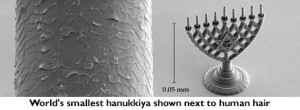 World's smallest hanukkiya shown next to human hair. [downloaded from http://www.cfhu.org/news/worlds-tiniest-menorah-built-by-hebrew-u-lab]