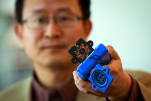 Ling Zang, a University of Utah professor of materials science and engineering, holds a prototype detector that uses a new type of carbon nanotube material for use in handheld scanners to detect explosives, toxic chemicals and illegal drugs. Zang and colleagues developed the new material, which will make such scanners quicker and more sensitive than today’s standard detection devices. Ling’s spinoff company, Vaporsens, plans to produce commercial versions of the new kind of scanner early next year. Courtesy: University of Utah