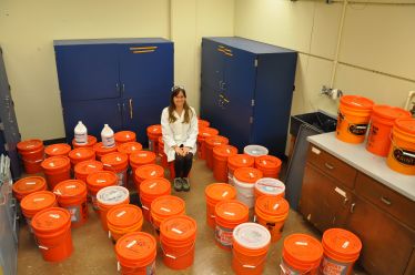 Alicia Taylor, a graduate student at UC Riverside, surrounded by buckets of effluent from the septic tank system she used for her research. Courtesy: University of California at Riverside