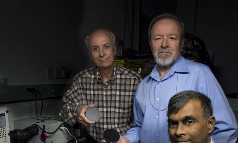 John Kolasinski (left), Ted Kostiuk (center), and Tilak Hewagama (right) hold mirrors made of carbon nanotubes in an epoxy resin. The mirror is being tested for potential use in a lightweight telescope specifically for CubeSat scientific investigations. Credit: NASA/W. Hrybyk